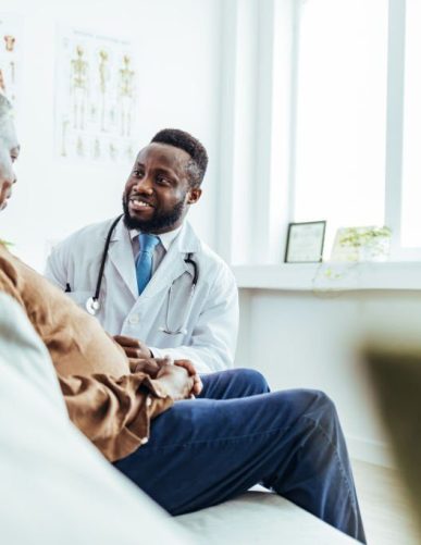 Male family doctor listening carefully to a senior man patient problems and symptoms